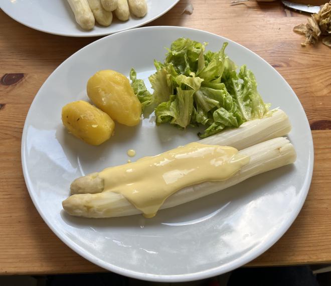 Cooked white asparagus with béchamel sauce, boiled potatoes and salad.